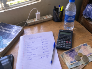 Handwritten semester allowance budget plan on a notebook in a Nigerian student hostel room