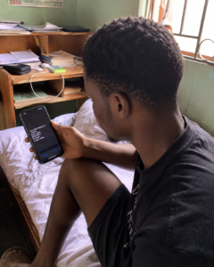 Nigerian student checking mobile data balance on phone in hostel room