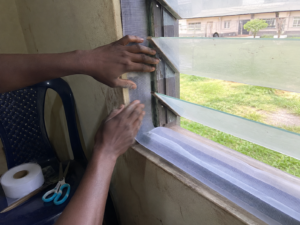 Self-adhesive mosquito mesh being fitted on a hostel window in Nigeria