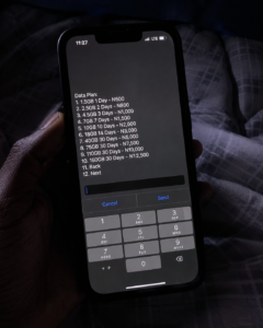 Phone screen showing night data plan USSD menu in a dark Nigerian hostel room