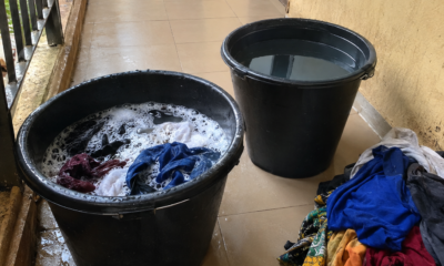 Two buckets and a pile of clothes set up for hand washing in a student hostel corridor
