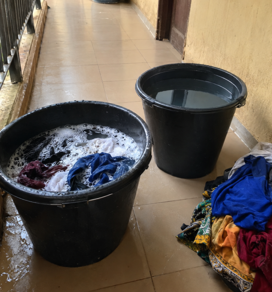 Two buckets and a pile of clothes set up for hand washing in a student hostel corridor